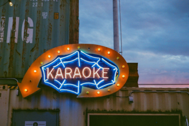 a large neon sign on the side of a building — Foto por Nikola Đuza na Unsplash
