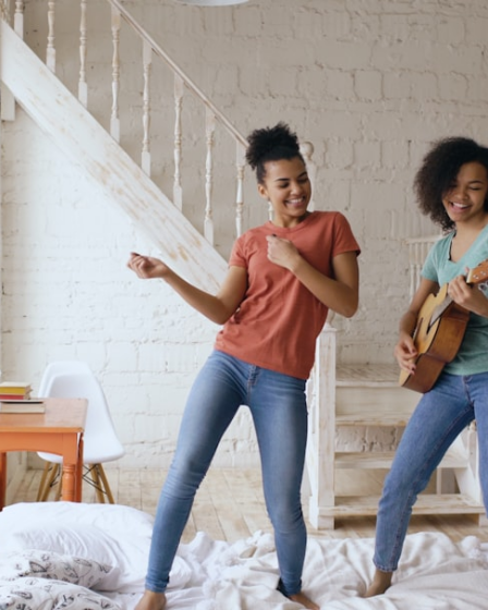 Two women dancing and playing guitar indoors. — Foto por Vitaly Gariev na Unsplash