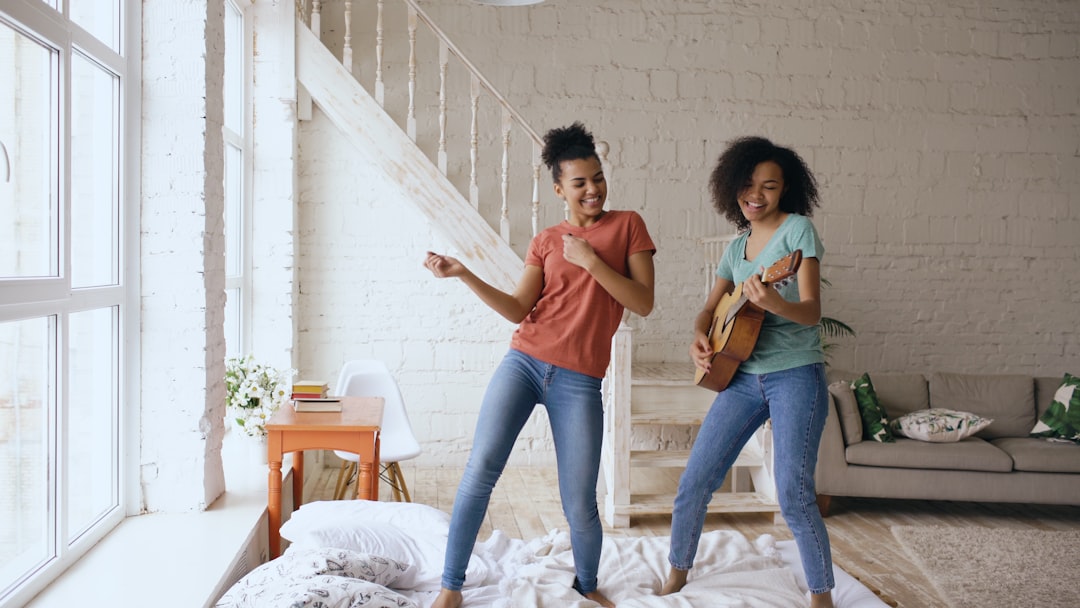 Two women dancing and playing guitar indoors. — Foto por Vitaly Gariev na Unsplash
