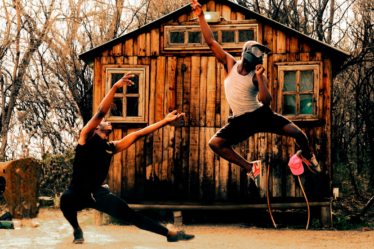 a couple of people playing frisbee in front of a log cabin — Foto por Jamal Selolwane na Unsplash