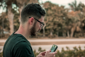 man looking down on his phone — Foto por Jacob Townsend na Unsplash
