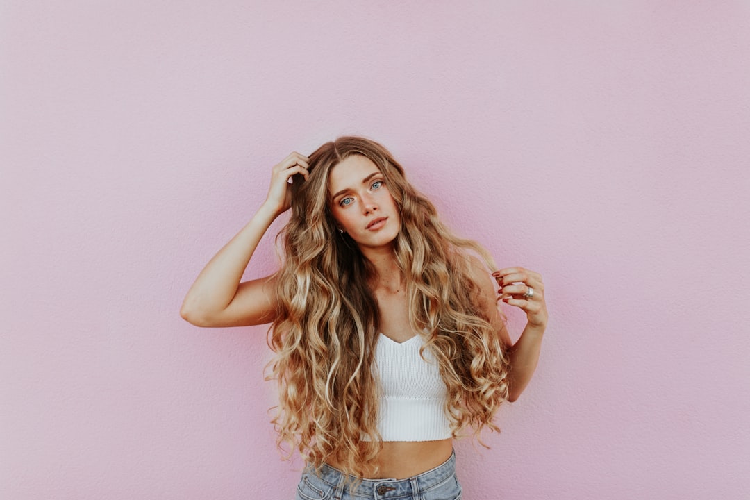 woman standing next to pink wall while scratching her head — Foto por averie woodard na Unsplash