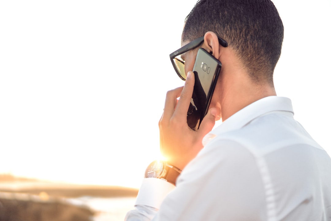man holding smartphone standing in front of calm body of water — Foto por Hassan OUAJBIR na Unsplash
